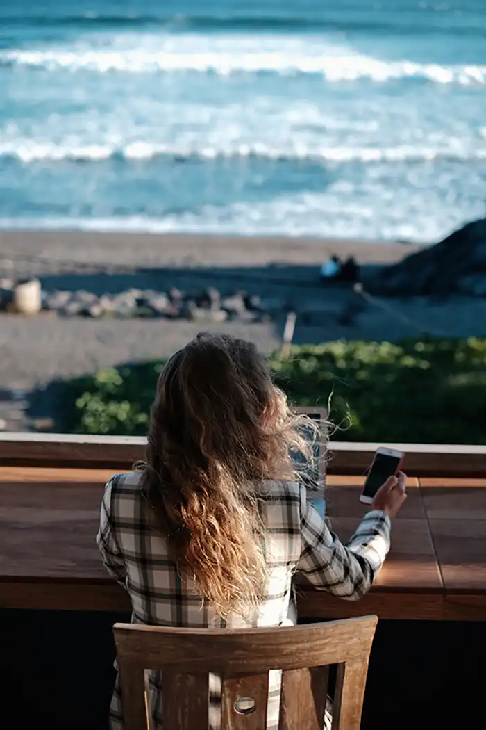 Lady sitting in front of beach at computer